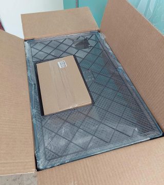 Contenido de la caja de la jaula Ferplast Favola antes del montaje, con base de plástico y piezas desmontadas